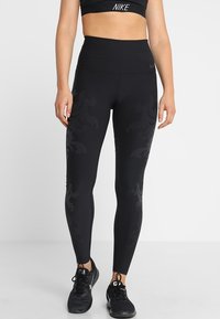 Svarta högmidjade leggings med en slät yta och subtilt mönster. Har Nike-logotyp och en snug fit-design för aktiv träning.
