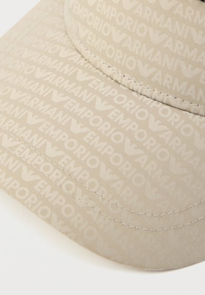 Bēša cepure ar visu virsmu pārklātu Emporio Armani logotipa rakstu. Izgatavota no faktūrētas auduma ar redzamām šuvēm uz saules aizsarga.