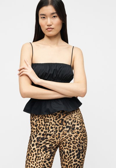 Μαύρο, συγκεντρωμένο τοπ με λεπτά λουριά και φαρδύ τελείωμα, συνδυασμένο με κολάν με λεοπάρ σχέδιο και υφή.