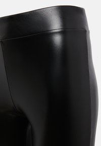 Zwarte neplederen leggings met een gladde textuur, een aansluitend ontwerp en een hoge tailleband met subtiele naaddetails.