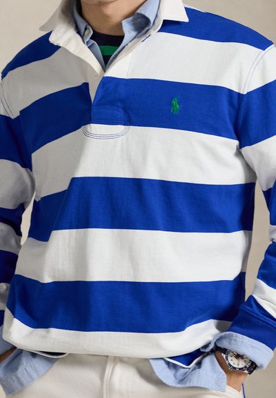 Blue and white striped long-sleeve polo shirt with a collar, featuring a green logo. Worn over a light blue shirt, paired with a watch.