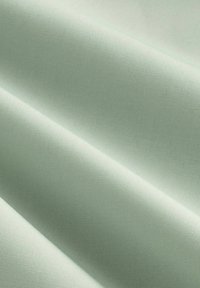 Tissu doux et lisse dans une couleur vert menthe clair, présentant une texture fine et un tissage uniforme. Un subtil éclat met en valeur le détail de la surface.