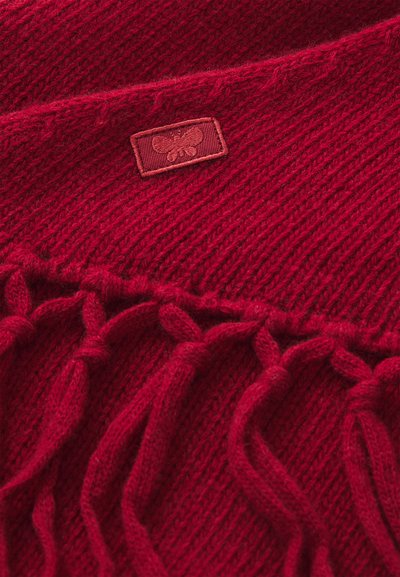 Red knitted scarf featuring a textured pattern, fringed ends, and a small embossed logo patch. Machine-washable wool blend material.