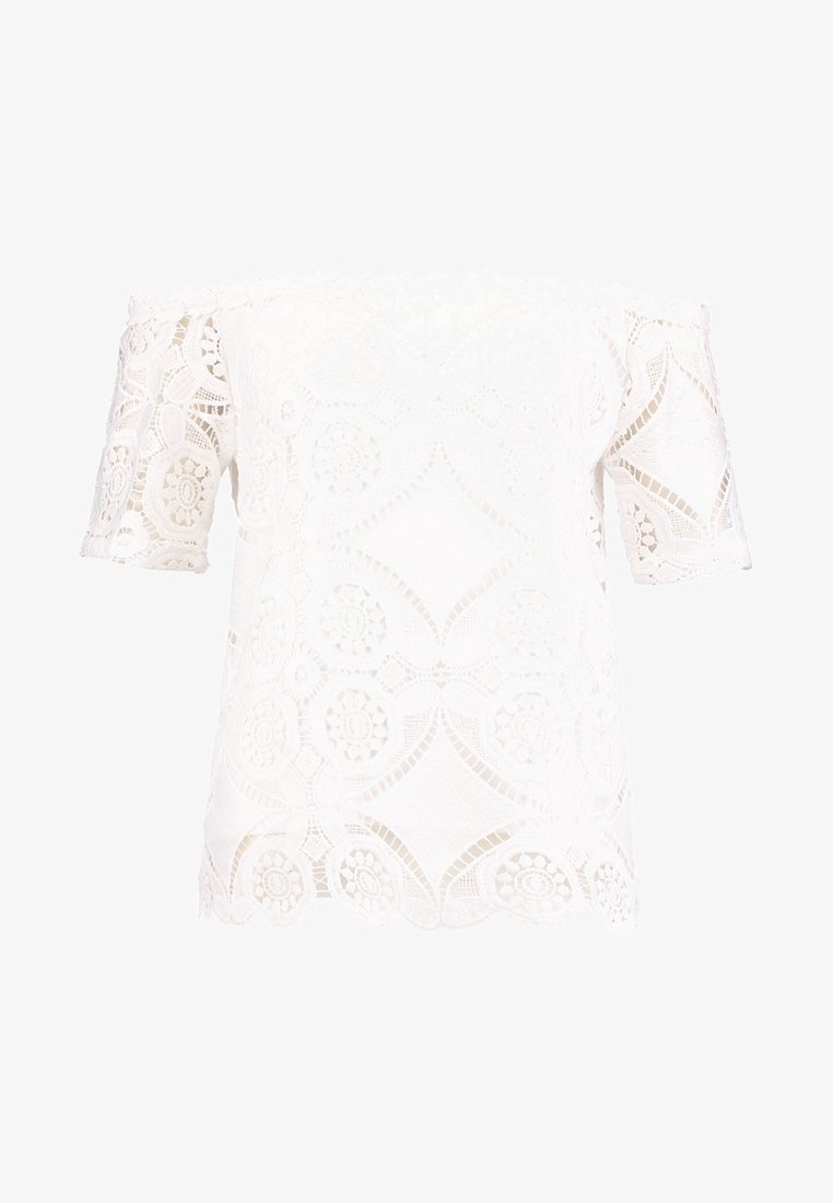 Haut blanc à épaules dénudées en dentelle avec des motifs floraux. Manches courtes et détail de bord festonné. Texture légère et transparente.