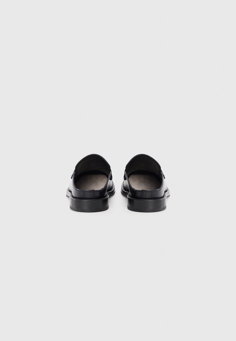 Zwarte leren instapschoenen met een ronde neus, lage hak en een soepele textuur. Minimalistisch ontwerp zonder zichtbare hardware of patronen.