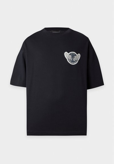 Μαύρο κοντομάνικο t-shirt με στρογγυλή λαιμόκοψη και μικρό έμβλημα με φτερά στο αριστερό στήθος που γράφει "Archive Emporio Armani."