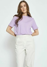 Alyvinė trumpas rankovės marškinėliai, pagaminti iš minkštos medžiagos, derinami su aukšta juosmens baltais kelnėmis. Paprastas apvalus kaklas ir laisvas siluetas.