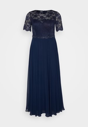 Granatowa sukienka wieczorowa z koronkowymi krótkimi rękawami, dopasowanym gorsetem i zwiewną spódnicą. Zdobiący pas z koralików dodaje faktury i wizualnego zainteresowania.