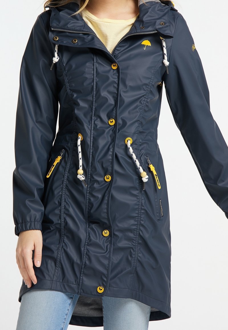 Navy waterproof jacket with a fitted design, drawstring hood, yellow accents, and multiple pockets; made from smooth, shiny material.