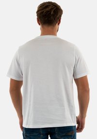 T-shirt bianco in cotone, con maniche corte e scollo rotondo, caratterizzato da una texture liscia. Sul retro non sono presenti grafiche o motivi.