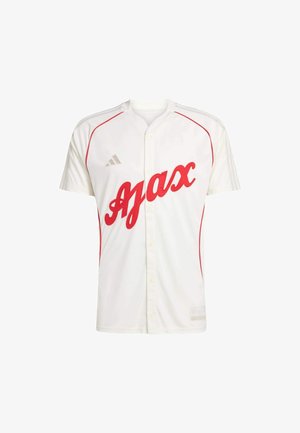 Biała sportowa koszulka z czerwoną nazwą "Ajax" na przodzie, zapinana na guziki, z czerwonym obszyciem na ramionach i bokach oraz logo Adidas na piersi.