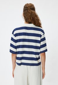 Navy ja valge triibuline lühikeste varrukatega T-särk, millel on soonikkrae ja lõdvestatud istuvus, valmistatud pehmest puuvilla segust.