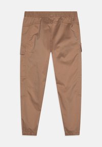 Cargo bukser i lysebrunt stof med elastisk talje og sammensunkne foringer. Sidelommer med klapper har synlige syninger.