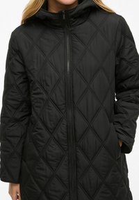Black quilted parka with diamond stitching, high collar, long sleeves, front zipper, and side pockets. Smooth texture and relaxed fit.