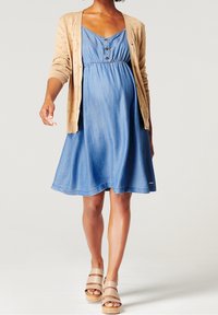 Abito in chambray blu con vita arricciata, bottoni e gonna svasata, abbinato a un cardigan beige strutturato e sandali con plateau color cammello.