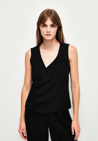 Top senza maniche nero con scollatura a V, caratterizzato da un design incrociato e cinque bottoni frontali. Tessuto morbido e dettaglio della tasca minimalista.