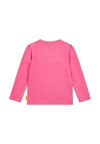 Camicia a maniche lunghe di un vivace colore rosa, realizzata in morbido cotone. Presenta un colletto rotondo e arricciature sulle spalle. Piccola etichetta gialla all'orlo.
