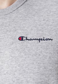 Felpa grigia con colletto rotondo, realizzata in tessuto testurizzato, con logo "Champion" ricamato in blu scuro e un'accattivante accentuazione rossa.