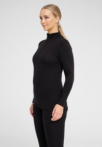 Sort langærmet top med lynlås i halsen, lavet af tekstureret stof. Den har et tætsiddende design, der går til hofterne, for en strømlinet silhuet.