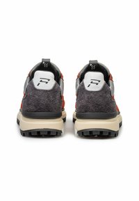 Due scarpe sportive viste da dietro, con un mix di suede arancione e grigio, dettagli in rete, suole in gomma nera e un logo di rilievo sul tallone.