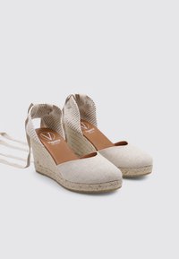 Wedges de esparto beige con parte superior de lona, plataforma de yute trenzado y diseño de cordones. Parte trasera abierta, puntera redonda, tacón texturizado.