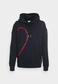 Granatowy hoodie wykonany z mieszanki bawełny, z dużym czerwonym nadrukiem z logo na boku, ze sznurkiem w kapturze i ściągaczami na mankietach.