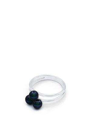 Bague argentée à double bande avec trois petites perles noires brillantes regroupées sur le dessus, fond blanc uni.