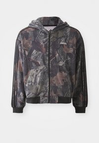 Hooded zip-up jacket featuring a camouflage pattern with brown and black leaf details, black cuffs, and three black stripes on sleeves.