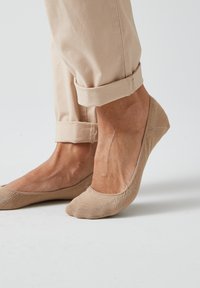 Chaussettes chevilles beiges en matériau tricoté texturé avec un design à coupe basse, présentant une finition lisse et des détails cousus le long des bords.