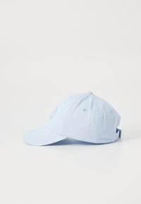 Lyseblå bomullsbaseballcaps med buet skjerm, justerbar stropp og synlige sømdetaljer. Har en subtil logo på forsiden.
