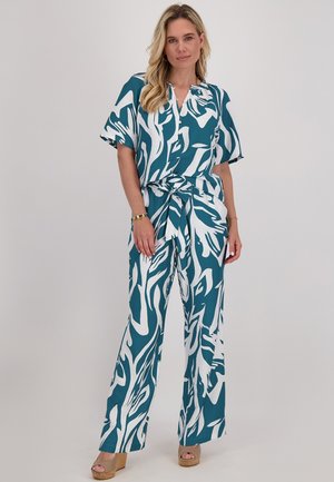 Een turquoise en witte jumpsuit met een patroon, korte mouwen, een V-hals en een strikceintuur, met losse, wijde broekspijpen.