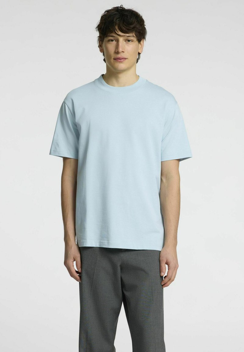 Šviesiai mėlynas trumpomis rankovėmis marškinėliai, pagaminti iš minkštos medvilnės. Sukurtas su apvalia iškirpte ir laisvu siluetu. Derinama su pilkais kelnėmis.