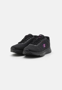 Svarte joggesko med strukturet mesh-overdel, rund tå og gummisåle. Har lilla detaljer på logoen og snørehullene.