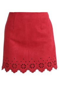 Jupe en daim rouge avec un ourlet festonné présentant des motifs floraux découpés. Texture lisse, forme structurée et deux poches avant.