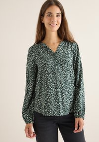 Grüne Bluse mit Knopfleiste, V-Ausschnitt, langen Ärmeln und einem ganzflächigen, abstrakten Muster in unterschiedlichen Grüntönen und Beige. Weicher, fließender Stoff.