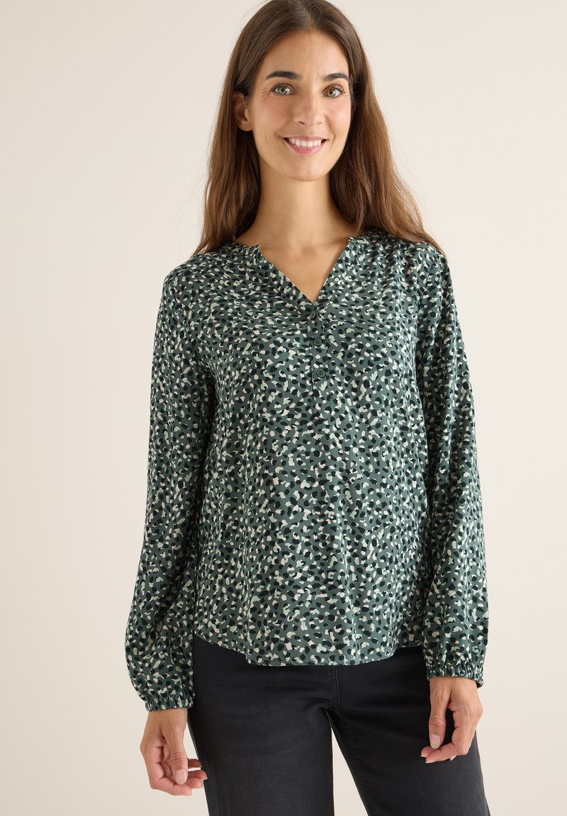Grüne Bluse mit Knopfleiste, V-Ausschnitt, langen Ärmeln und einem ganzflächigen, abstrakten Muster in unterschiedlichen Grüntönen und Beige. Weicher, fließender Stoff.