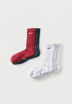 Drei Paar gerippte Sneakersocken in Rot, Grün und Blau gestapelt, neben drei weißen Paaren mit roten und marineblauen Logos.
