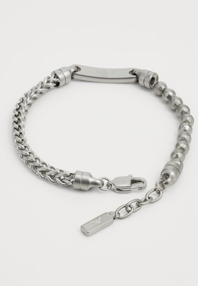 Sömlös armband med en blandad design av kedjelänkar och bead-segment, med en lås och en liten tag-detail. Slät metallfinish.