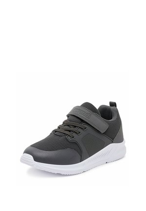 Zapatilla deportiva de color gris oscuro para niño, con parte superior de malla, cierre de velcro, cordones y suela de goma blanca.