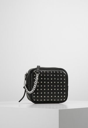 Sort rektangulær crossbody taske med sølvnitter foran og en sølvkæde-rem, placeret på en hvid overflade mod en ensartet baggrund.