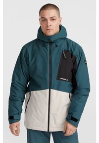 Chaqueta de invierno con bloques de color en verde azulado y negro, con un bolsillo con cremallera, capucha, cierre con cremallera y puños ajustables. Fabricada con material resistente al agua.