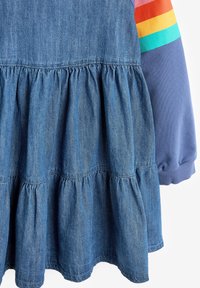 Abito in denim con una gonna a balze raccolte, maniche lunghe blu e accenti a strisce multicolori sulla manica destra.