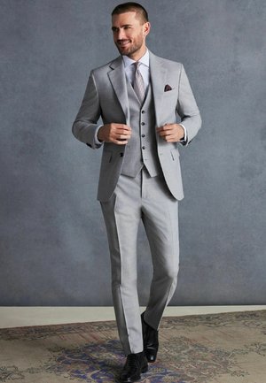 Traje de tres piezas gris claro con un diseño ajustado, cuello con muesca, combinado con una camisa blanca y una corbata texturizada.