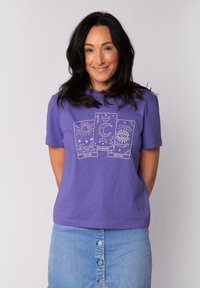 T-shirt en coton violet avec trois illustrations de cartes de tarot : soleil, lune et destin, soulignées en blanc. Manches courtes et coupe décontractée.