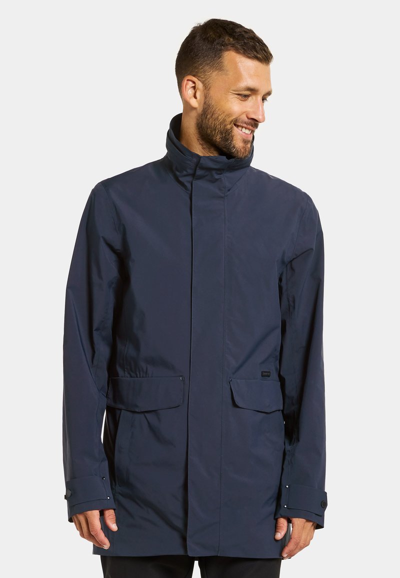 Wasserabweisende dunkelblaue Jacke mit hohem Kragen, zwei Fronttaschen und Druckknopfärmeln. Elegantes Design mit glatter, matter Oberfläche.