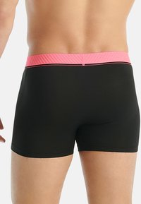 Czarne spodenki kąpielowe z gładkiego materiału, z prążkowanym różowym paskiem ze wstawką w postaci cienkiej czarnej linii u góry.
