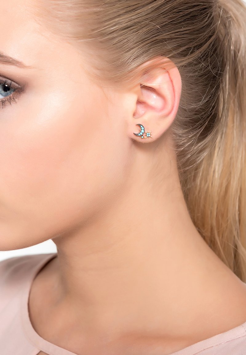 Pendientes de turquesa y plata diseñados en forma de media luna con pequeños acentos de estrella, que cuentan con un acabado metálico suave y detalles brillantes.