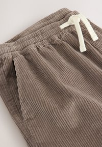 Braune Cordhosen mit strukturierter Oberfläche, einem elastischen Bund und einem kontrastierenden cremefarbenen Kordelzug. Zwei Seitentaschen sind enthalten.
