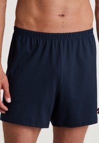 Shorts en coton bleu marine avec une taille élastique, présentant une texture lisse et un design simple sans poches ni motifs.