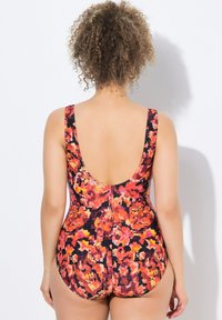 Maillot de bain une pièce avec un motif floral coloré dans des teintes d'orange, de rose et de noir ; il possède des bretelles larges et un design à dos nu.